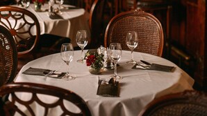A restaurant interior with round tables, chairs, and a bar area.