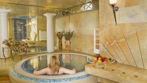 A spa area with a hot tub, a wooden bench, and a fruit bowl.