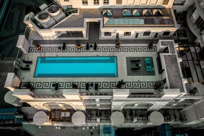 Vista aérea de um hotel com piscina central, áreas de estar ao ar livre e design arquitetônico moderno.
