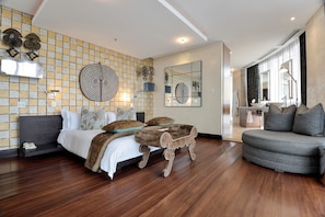 Een moderne slaapkamer met een groot bed, een ronde spiegel en een bank.