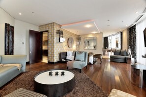 Een ruime woonkamer met een modern design, met een grote ronde salontafel, een bank en een zithoek met een kamerbreed tapijt.