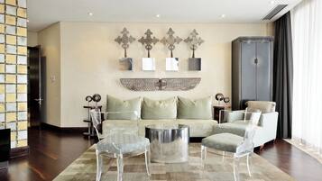 A modern living room with a sofa, two clear chairs, a coffee table, and decorative wall art.