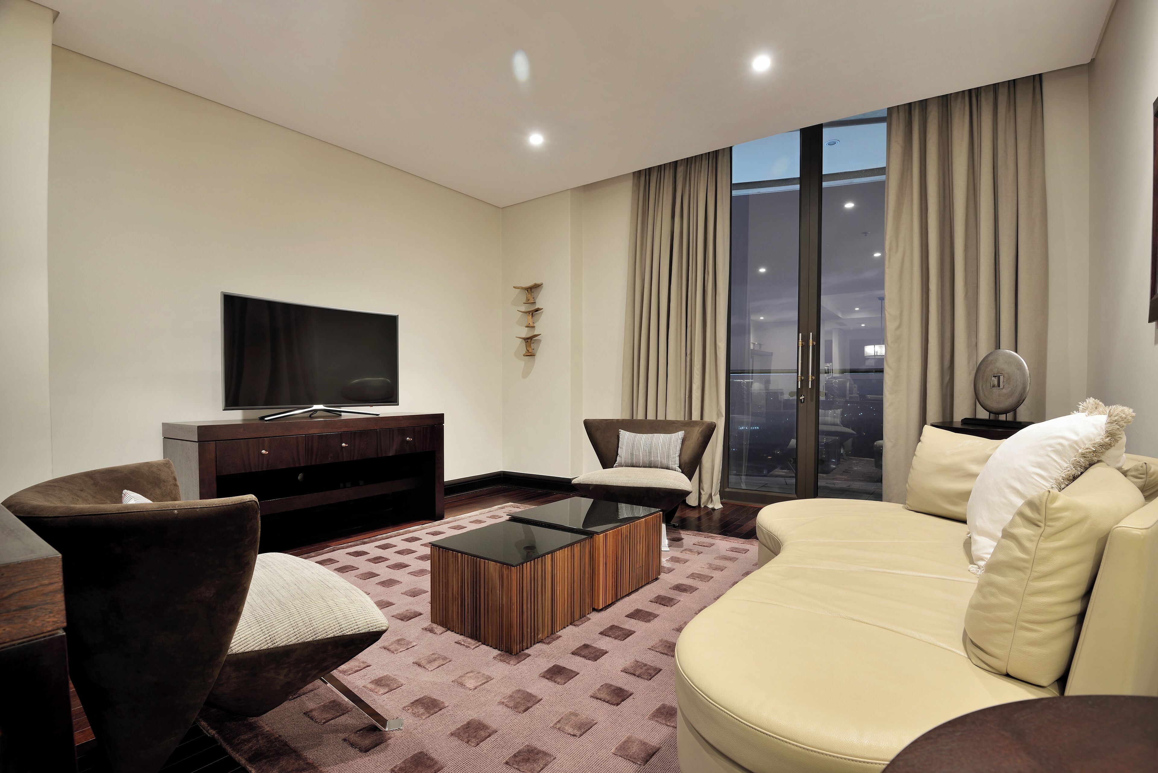 A modern living room with a flat-screen TV, a sofa, a chair, and a coffee table.