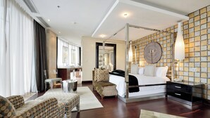 Een moderne hotelkamer met een groot bed, een zithoek met een gestreept sofa, een bijzettafeltje en een decoratief object aan de muur.
