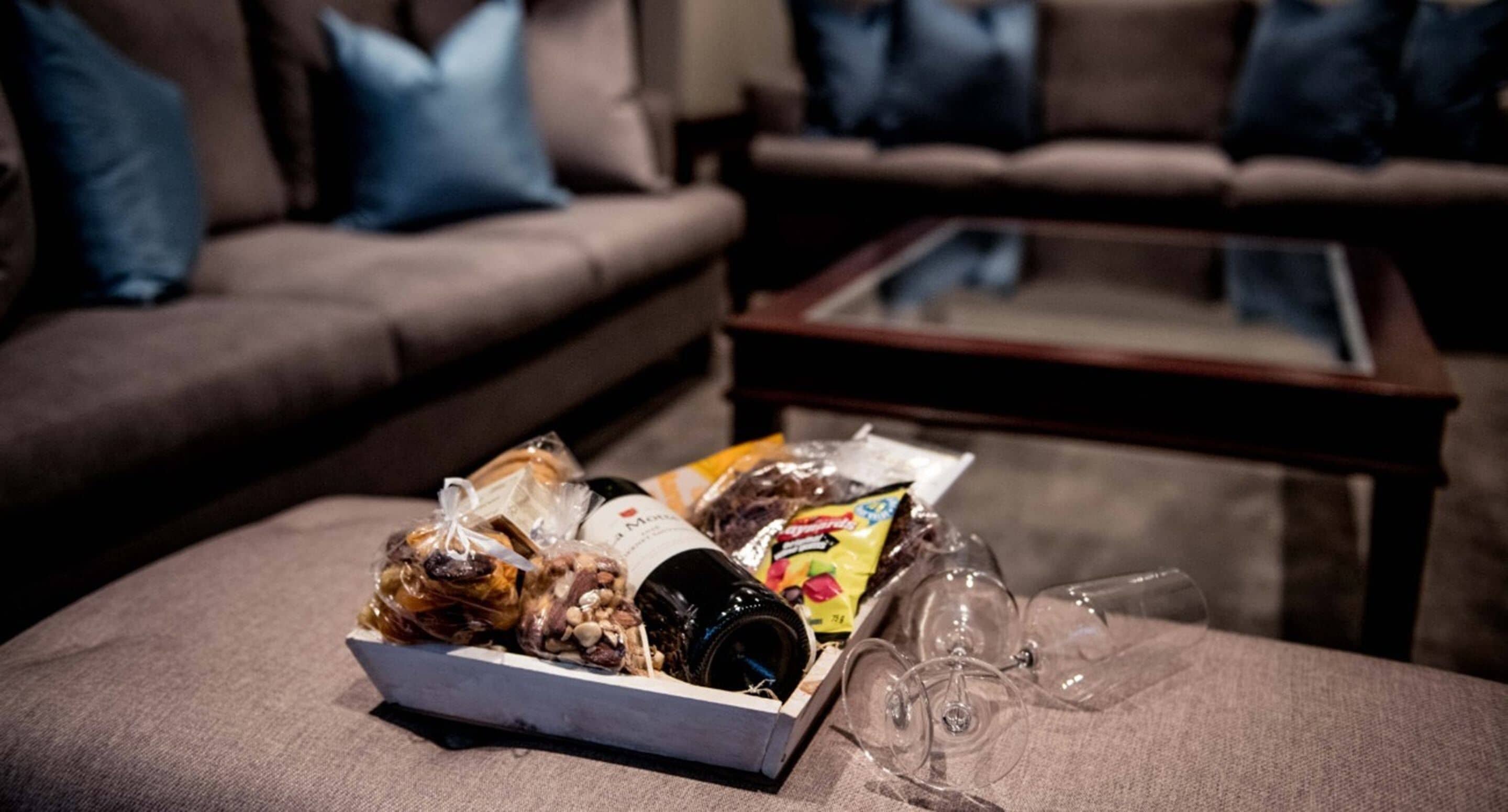 Un salón con sofá, una mesita de centro y una caja de aperitivos y bebidas.