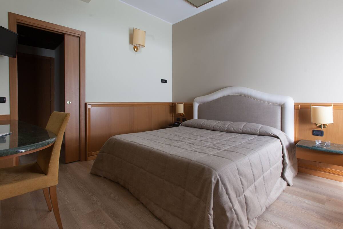 Una camera d'albergo con un letto, una scrivania e una sedia.