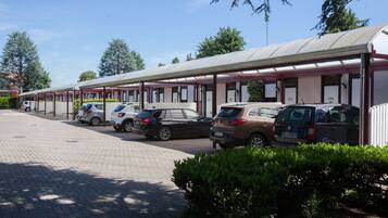 A row of motel-style cabins with numbered doors, parked cars, and a paved driveway.