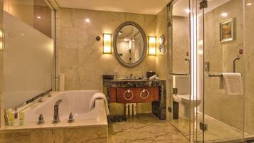 A modern bathroom with a marble floor, a freestanding bathtub, a glass-enclosed shower, and a vanity with a large mirror.
