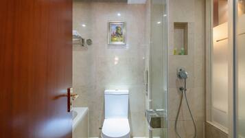 A modern bathroom with a toilet, a shower, and a glass-enclosed shower area.