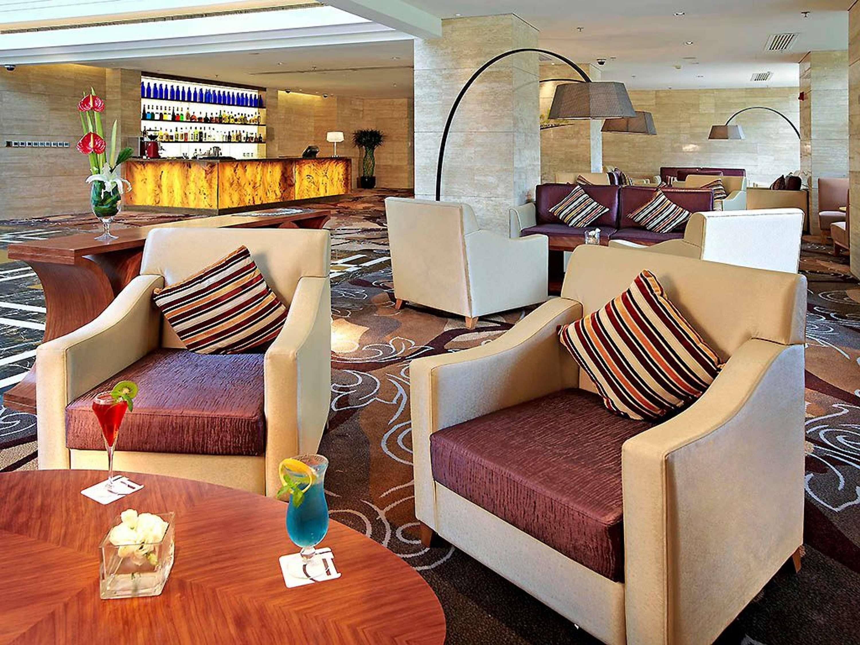 Um saguão de hotel com arranjos de assentos, área de bar e balcão de recepção.