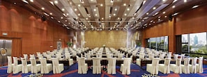 A conference room with rows of tables and chairs, large windows, and a city view. - Pullman Xiamen Powerlong (Xiamen)