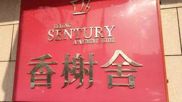 A sign for Beijing Sentury Apartment Hotel with a crown symbol above the name.