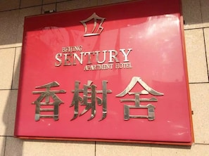 Letrero del Hotel Apartamentos Sentury Beijing, con un símbolo de corona sobre el nombre.