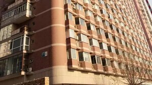 Un edificio alto de varios pisos con fachada curva, que cuenta con numerosos balcones y un patrón uniforme en las ventanas.