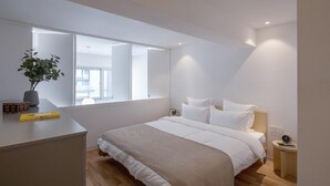 A modern bedroom with a large bed, bedside tables, a bedside plant, and a window. - New Beacon International Hotel - Shanghai (Shanghai)