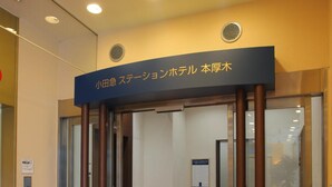 L’entrée d’un hôtel, avec une enseigne en japonais, une porte vitrée et un sol carrelé.