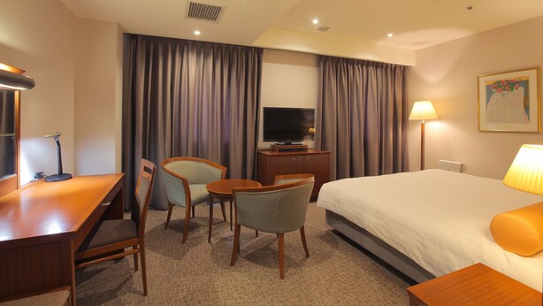 Une chambre d’hôtel équipée d’un lit, d’un bureau, de chaises, d’une télévision et d’une lampe.