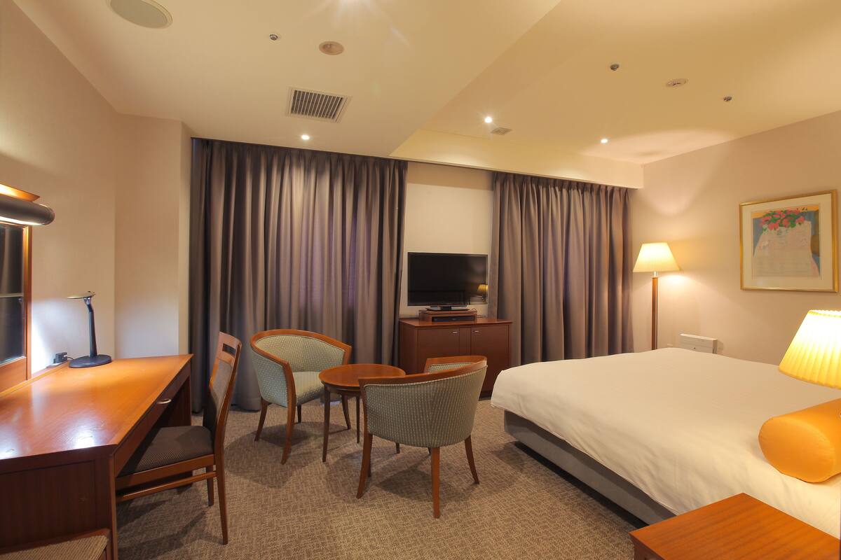 Une chambre d’hôtel équipée d’un lit, d’un bureau, de chaises, d’une télévision et d’une lampe.