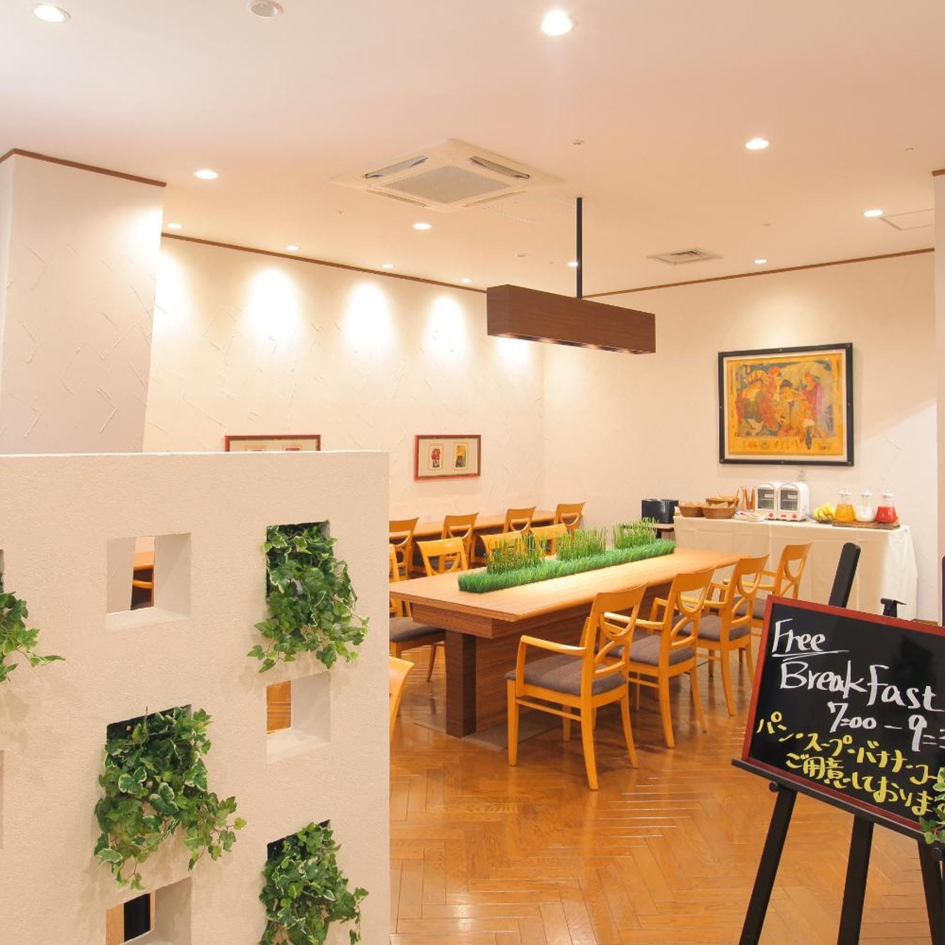 A restaurant interior with a long wooden table, chairs, and a sign offering free breakfast.