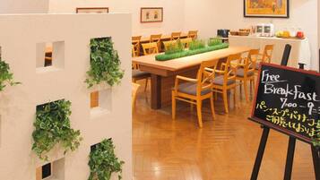 A restaurant interior with a long wooden table, chairs, and a sign offering free breakfast.