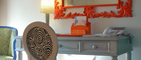 A room with a desk, a chair, a mirror, and a lamp.
