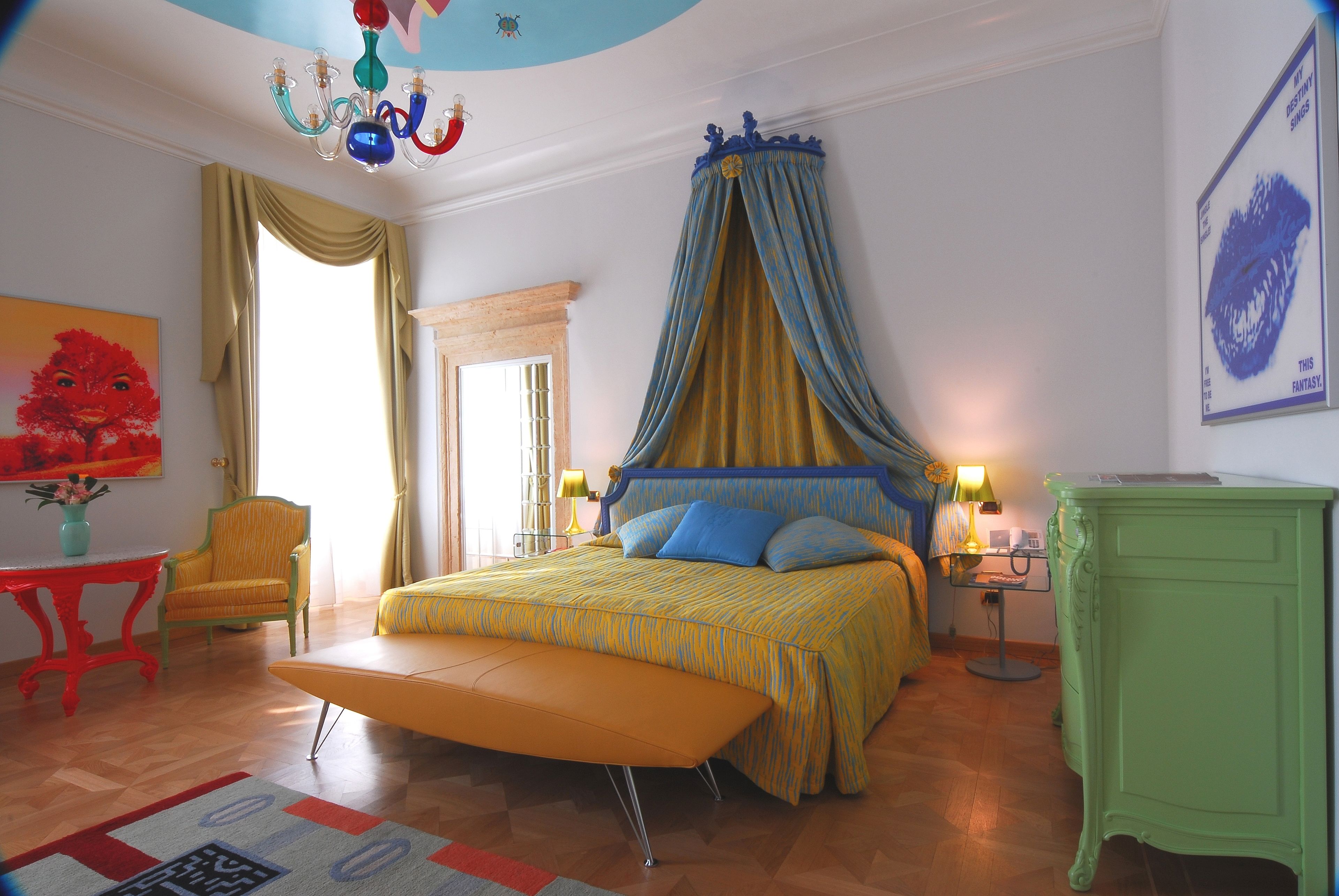 Un dormitorio con cama, una silla, una mesa y una lámpara.