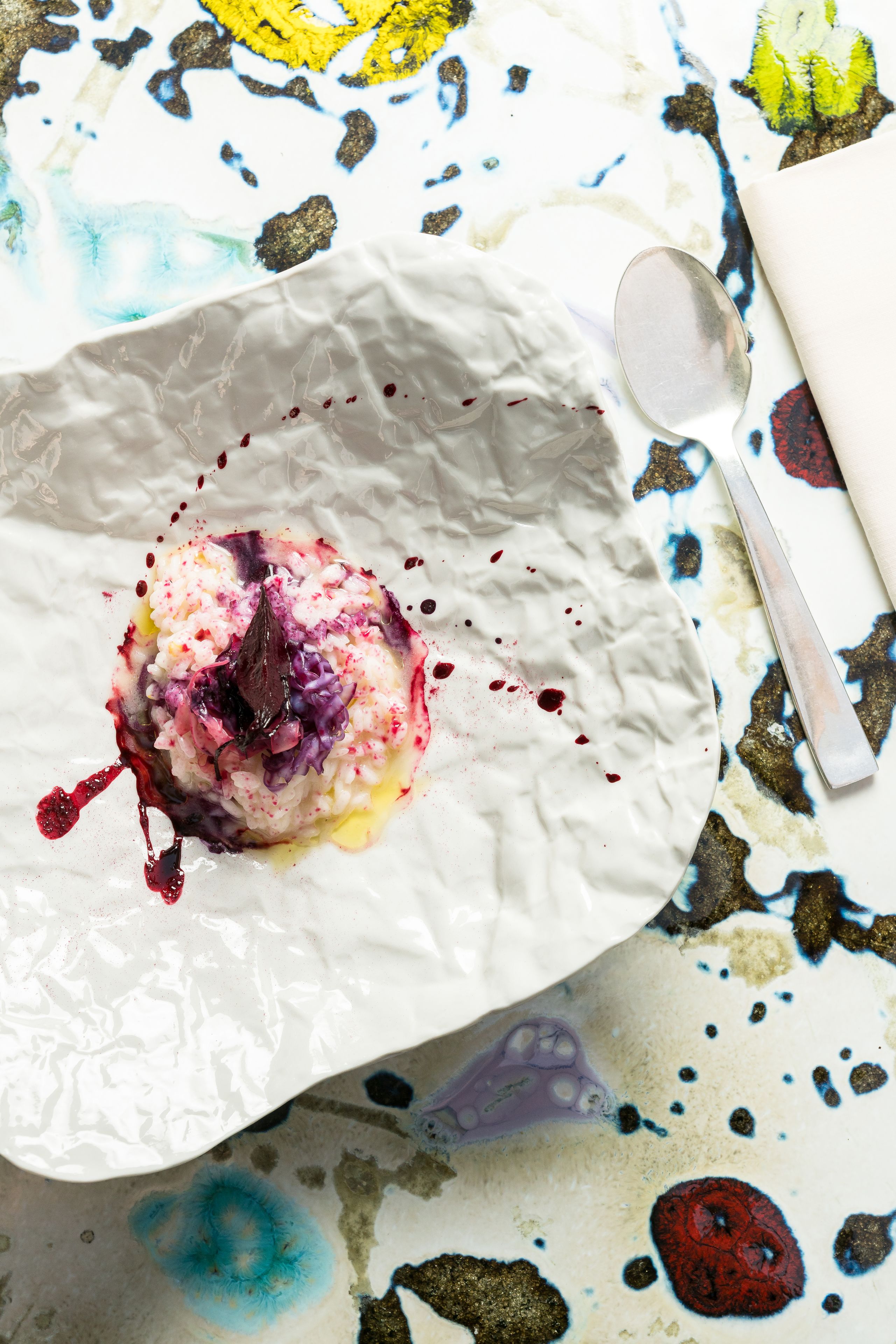 Une assiette blanche sur laquelle se trouve un dessert, posée sur une table ornée d’un motif abstrait aux couleurs vives.