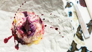 Une assiette blanche sur laquelle se trouve un dessert, posée sur une table ornée d’un motif abstrait aux couleurs vives.
