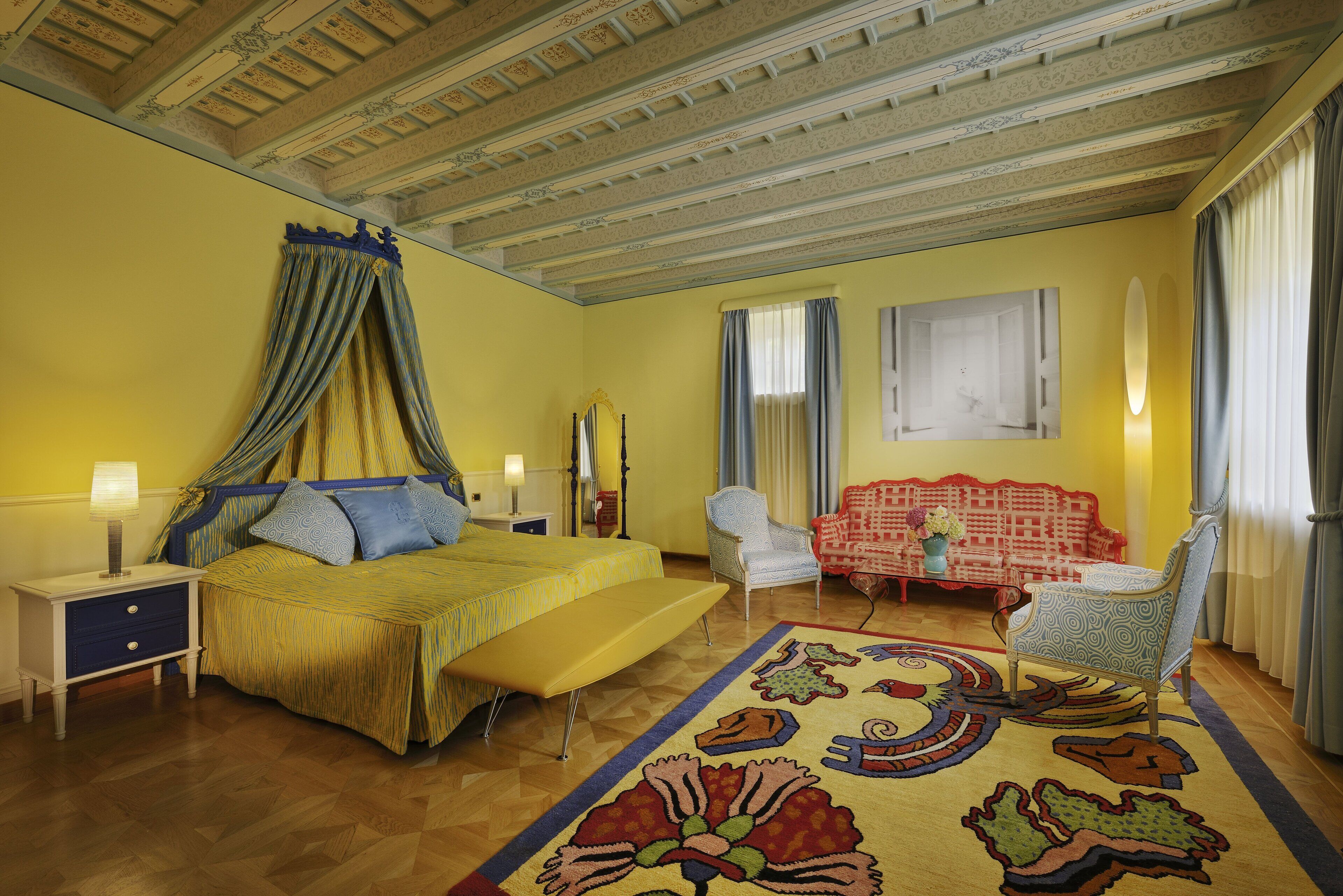A bedroom with a bed, bedside table, chair, and a sofa.