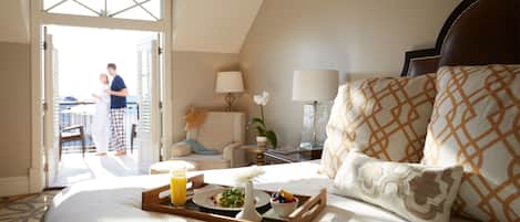 A hotel room with a bed, a tray with breakfast, a lamp, and a view of the outside.