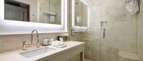 A modern bathroom with a large mirror, a sink, and a glass-enclosed shower.