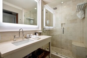 A modern bathroom with a large mirror, a sink, and a glass-enclosed shower.