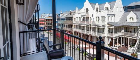 A balcony with wicker furniture, a view of historic buildings, and a clear blue sky.
