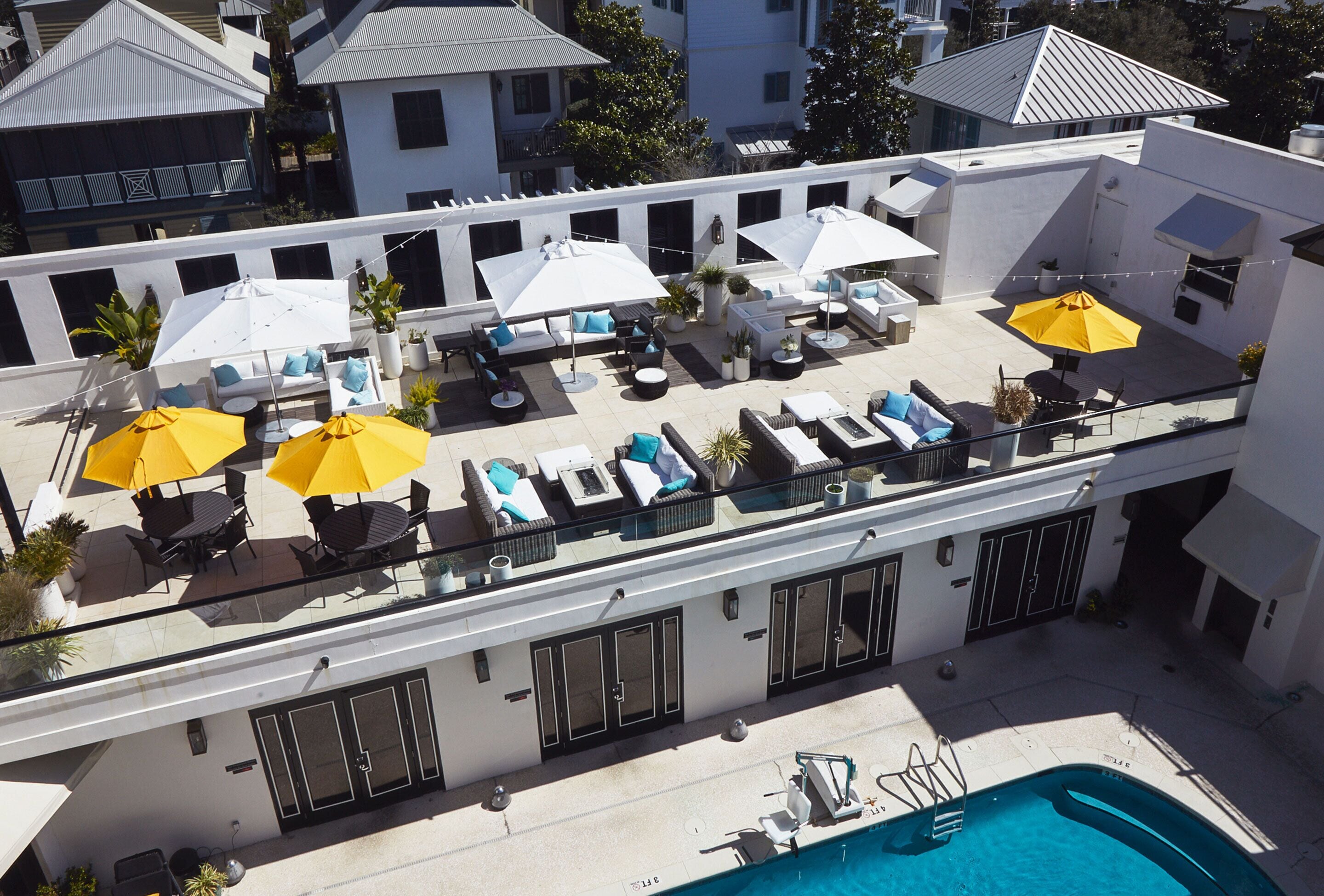Un espace piscine aménagé sur le toit, avec des chaises longues, des parasols et une piscine.