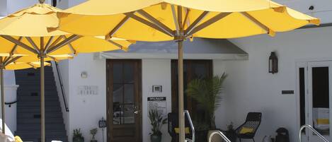 Zona de piscina con sombrillas, sillas de descanso y una escalera que lleva a un nivel superior.