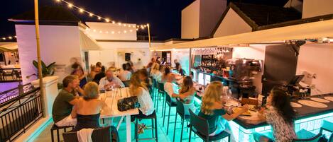An outdoor bar area with string lights, tables, and chairs.