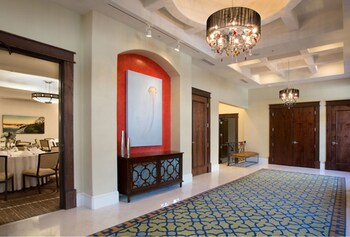 A hotel room with a large bed, two bedside tables with lamps, a bench, a door, and a window with curtains. at The Pearl Hotel