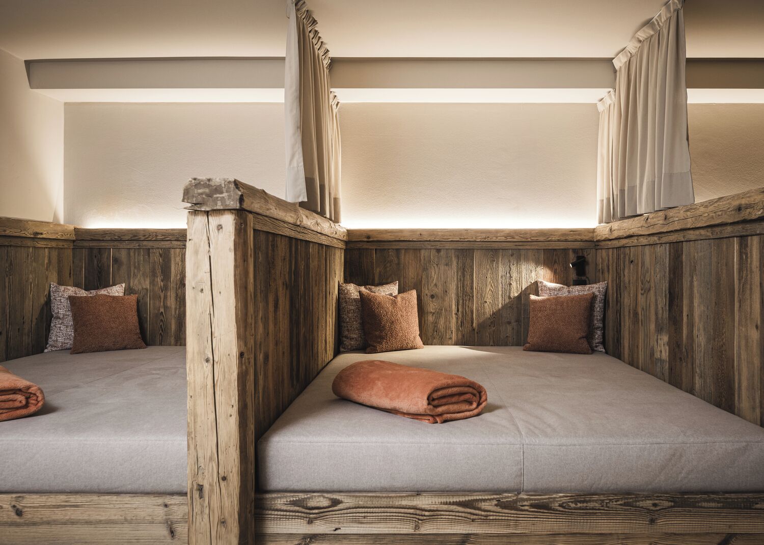 A room with two beds, wooden paneling, and a canopy bed.