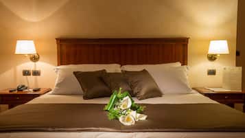 A neatly made bed with a brown headboard, two bedside lamps, and a floral arrangement on the bed.