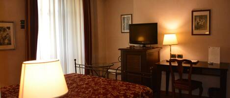 Une chambre d’hôtel avec un lit, un bureau, une chaise, une télévision et une lampe.