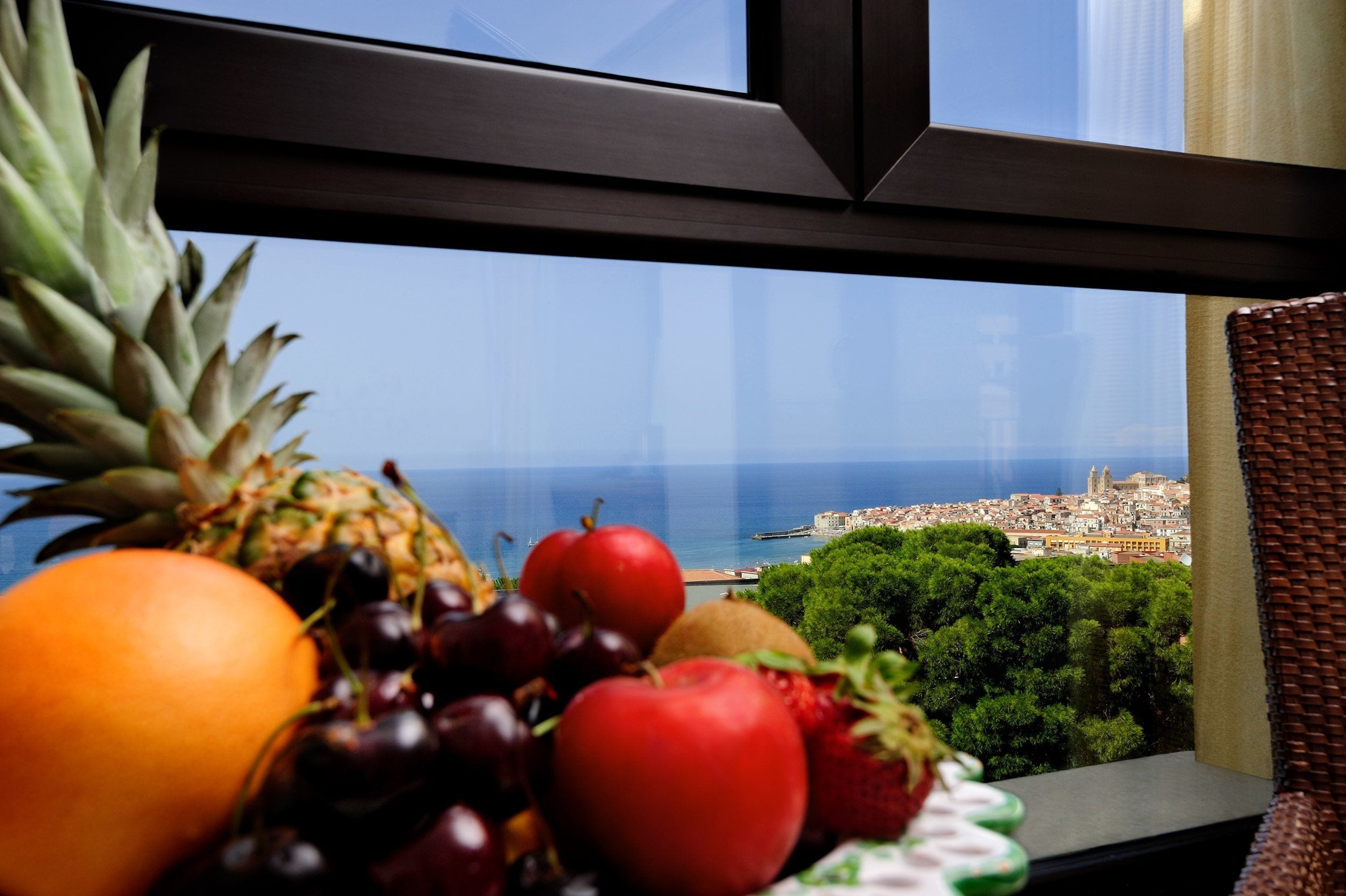 Obstschale auf einem Fensterbrett mit Blick auf eine Küstenstadt.