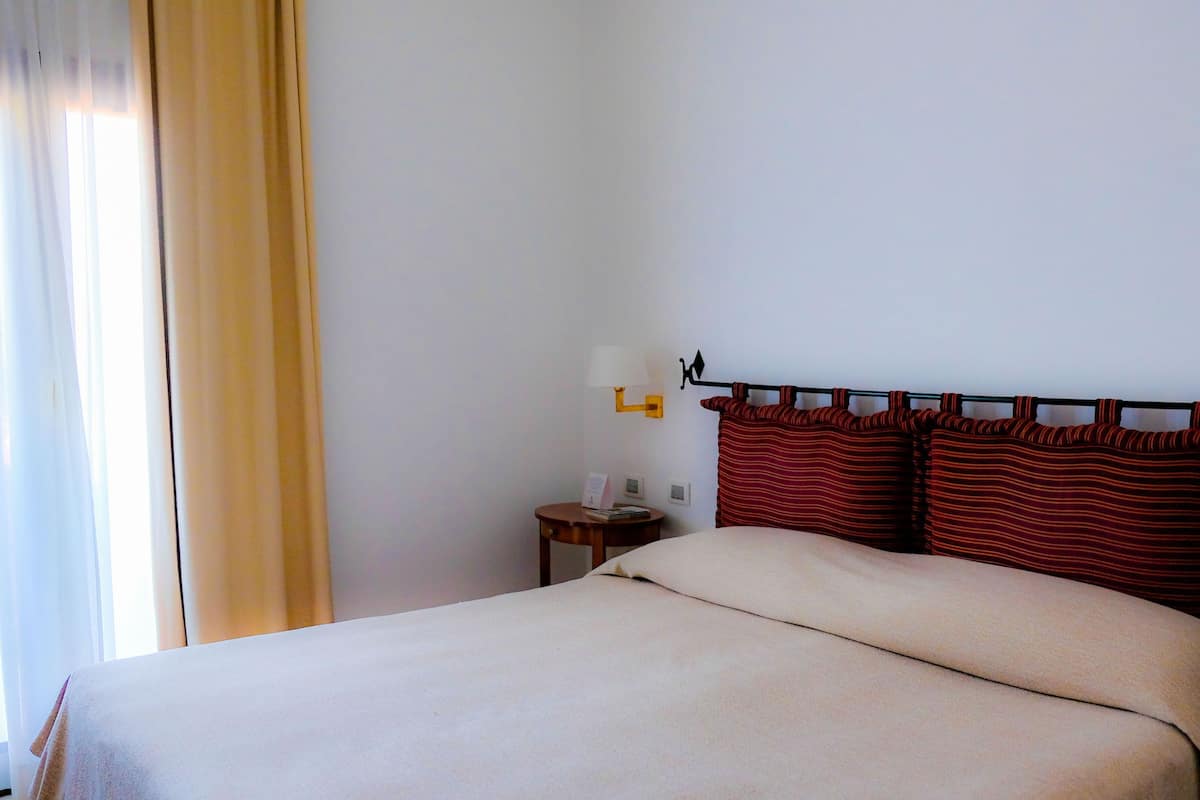 A hotel room with a bed, a nightstand, a lamp, and a telephone.