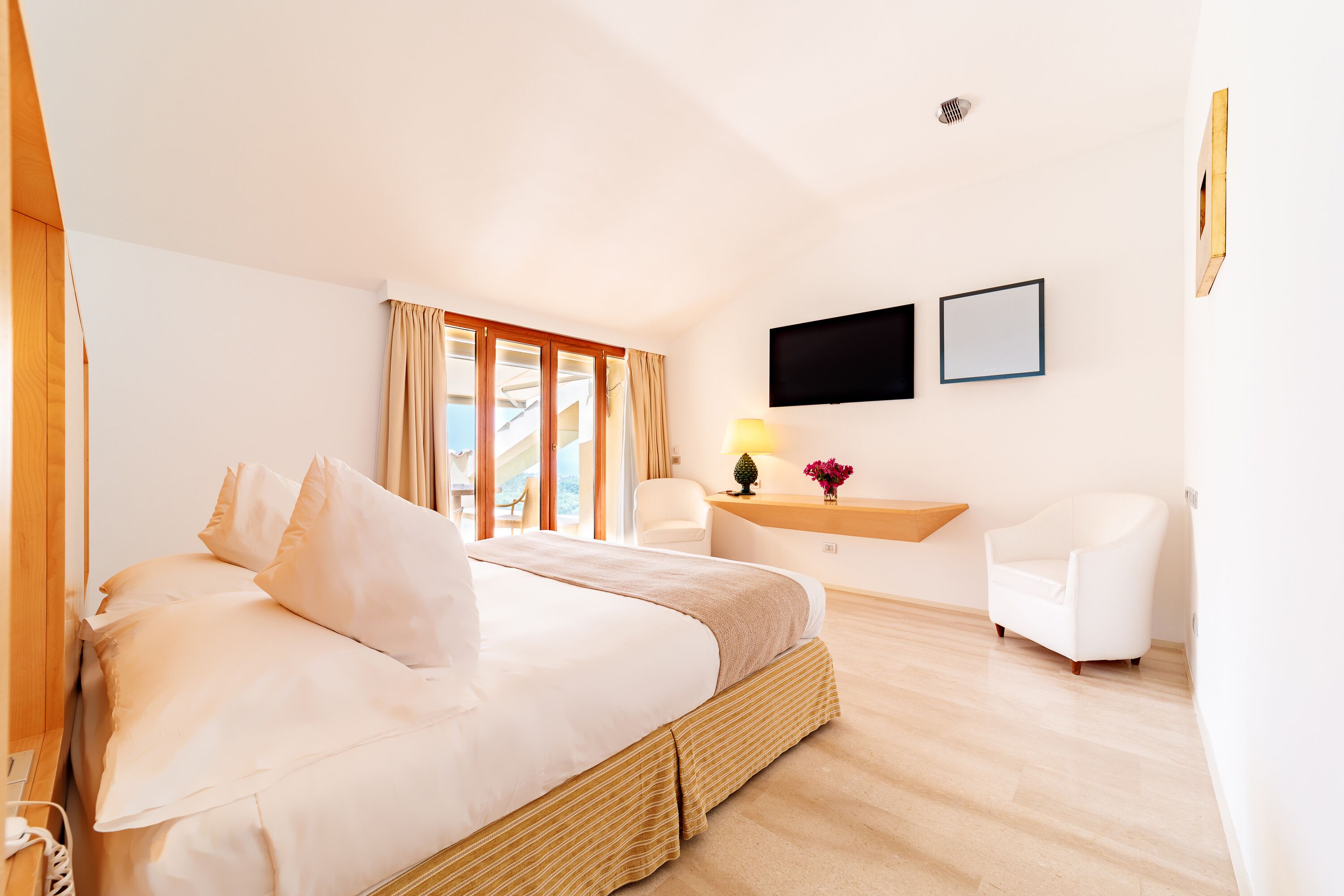 A hotel room with a bed, a desk, a chair, and a TV.