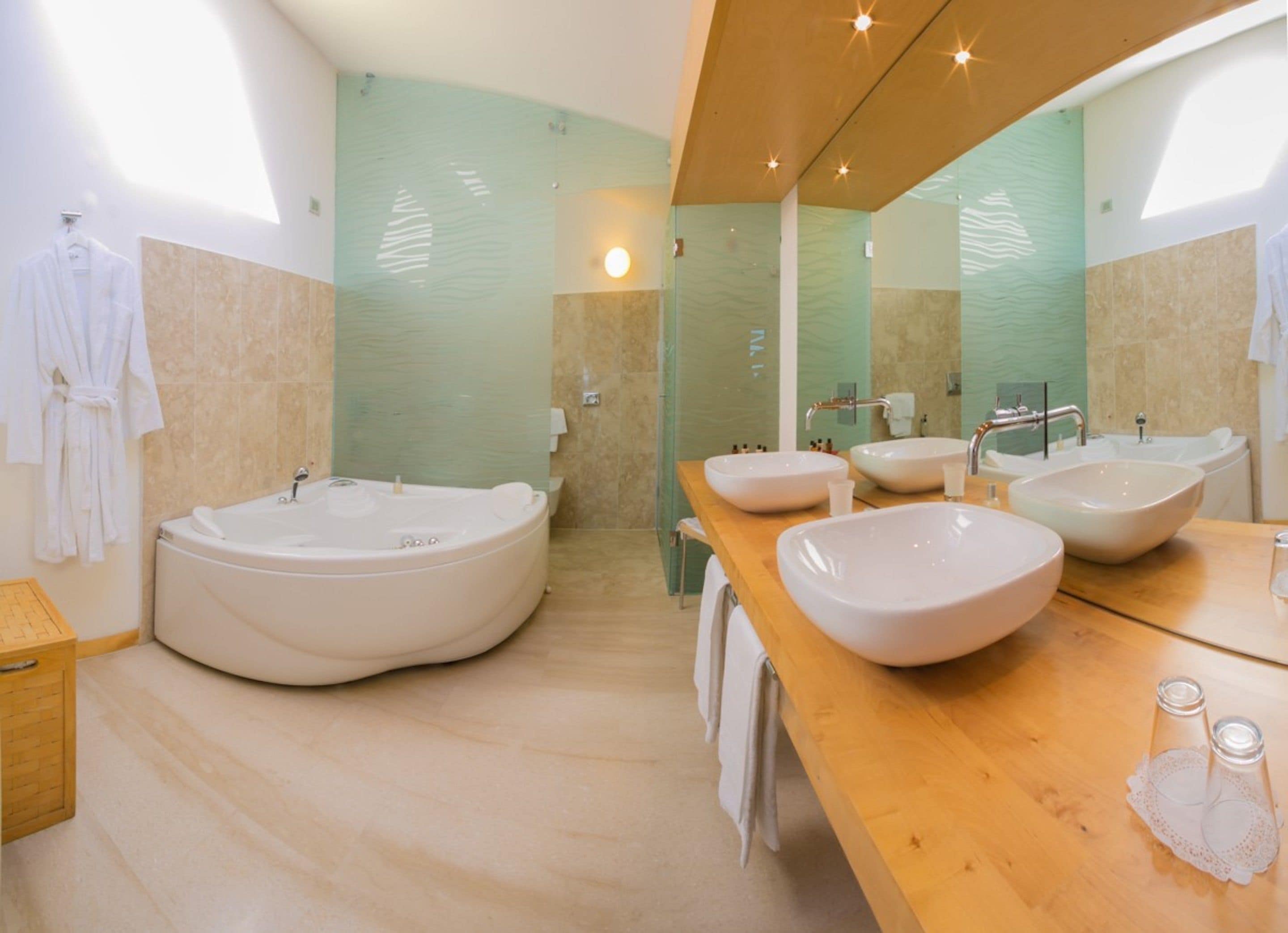 Ein modernes Badezimmer mit einer großzügigen, freistehenden Badewanne, zwei Waschbecken und einem Waschtisch mit Spiegel.