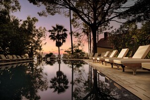 Una piscina al aire libre, sombrillas, sillones reclinables de piscina