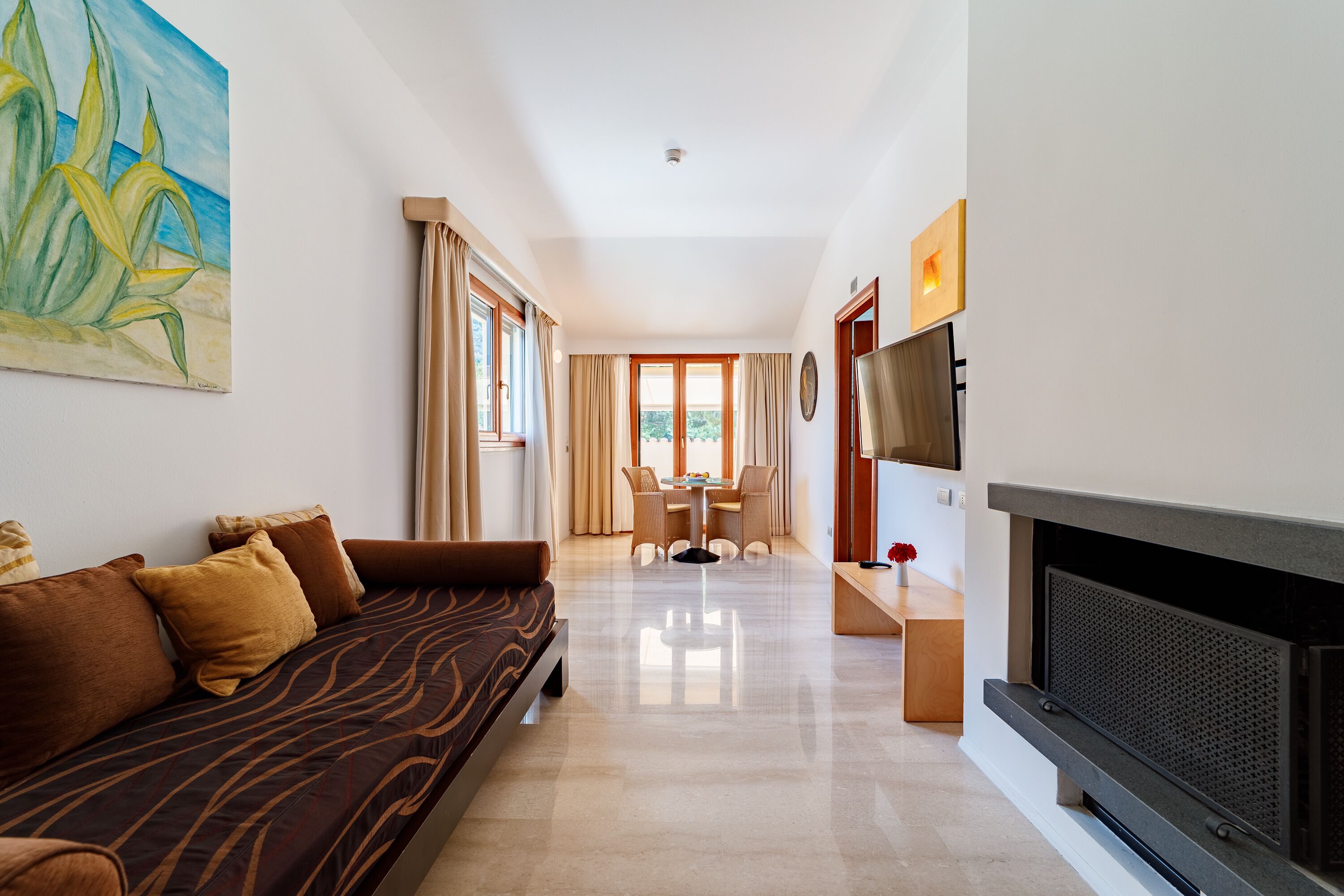 A modern living room with a sofa, a flat-screen TV, and a fireplace.
