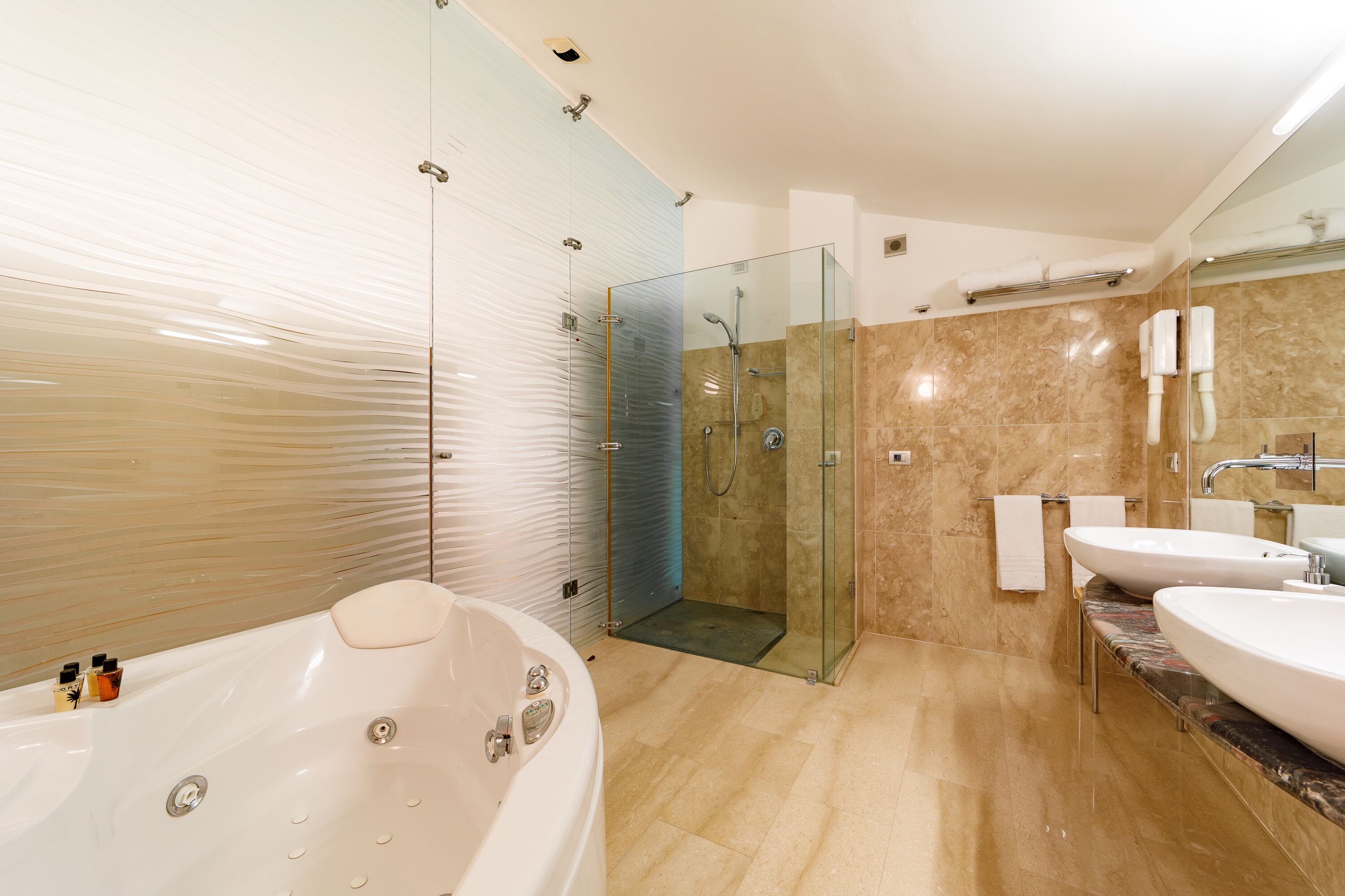A modern bathroom with a glass-enclosed shower, a freestanding bathtub, and two sinks.