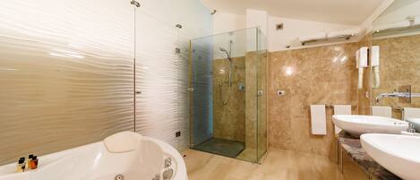 A modern bathroom with a glass-enclosed shower, a freestanding bathtub, and two sinks.