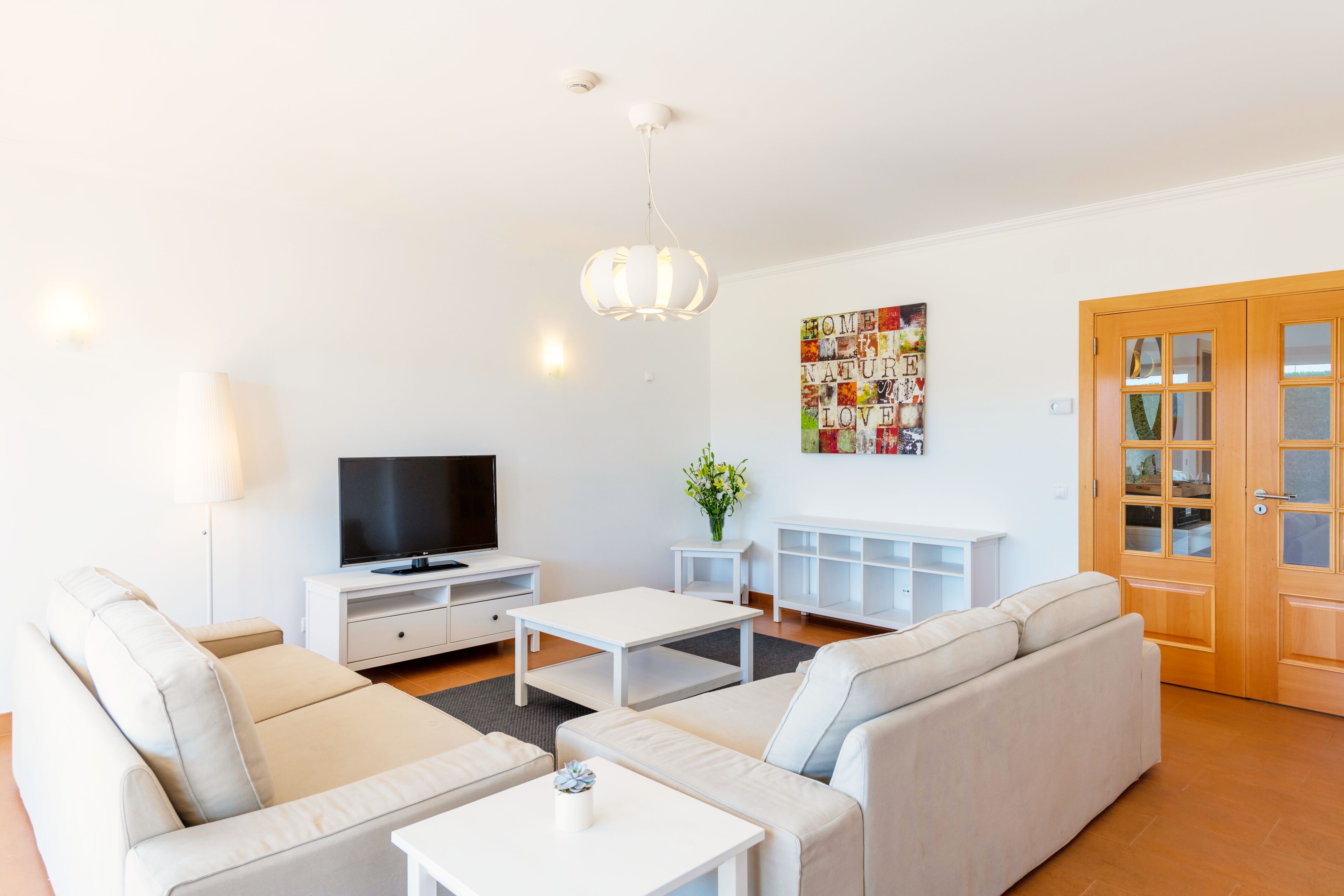 Una sala de estar moderna con un conjunto de sofá, un televisor, una mesa de centro y un adorno de pared.