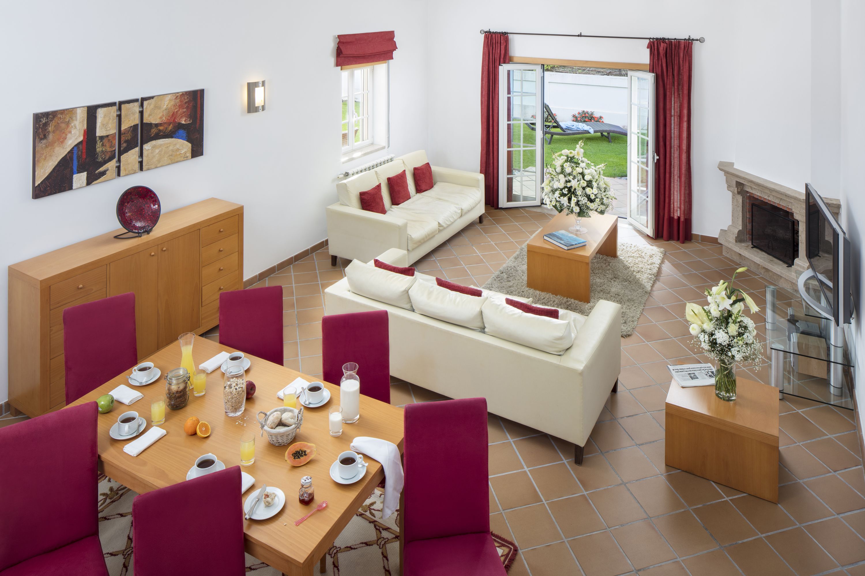 Ein modernes Wohnzimmer mit Essbereich, einer Sofagarnitur, einem Kamin und Blick ins Freie.